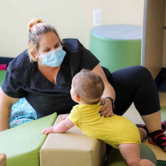 Daycare teacher in mask with a baby