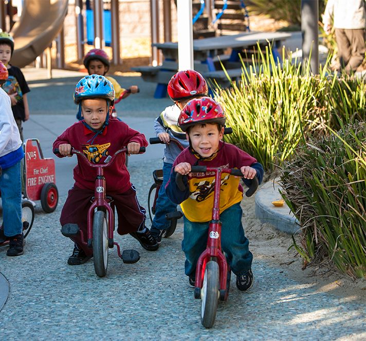 Group of young children wearing helmets and riding bicycles outside