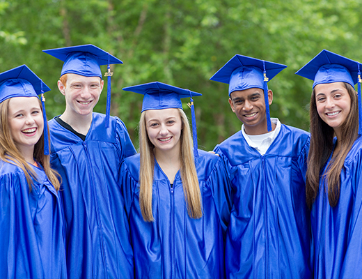 Group of co-ed high-schoolers wearing caps and gowns at graduation