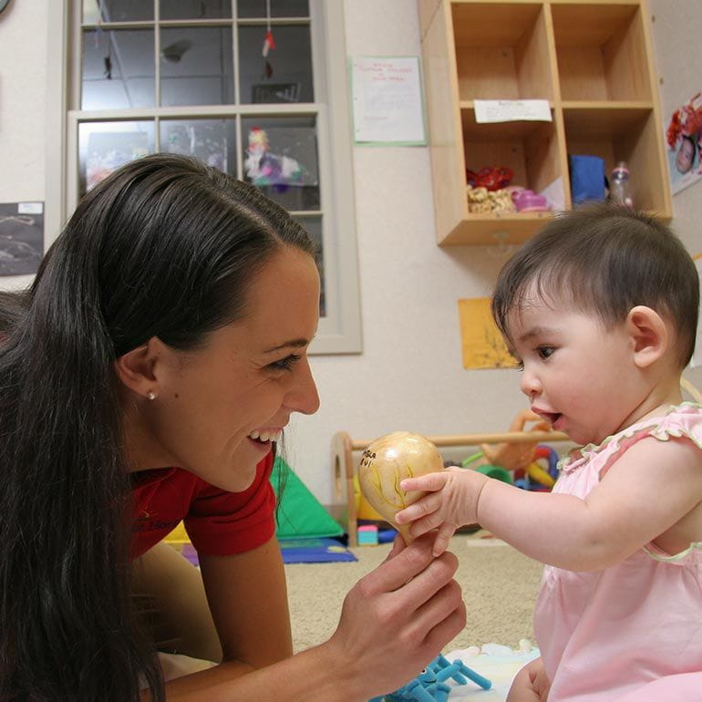 Bright Horizons teacher and infant playing with maracas