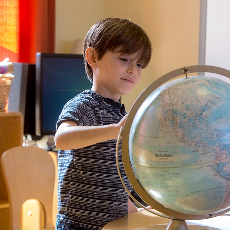 Bright Horizons kindergarten Prep Student studying a globe