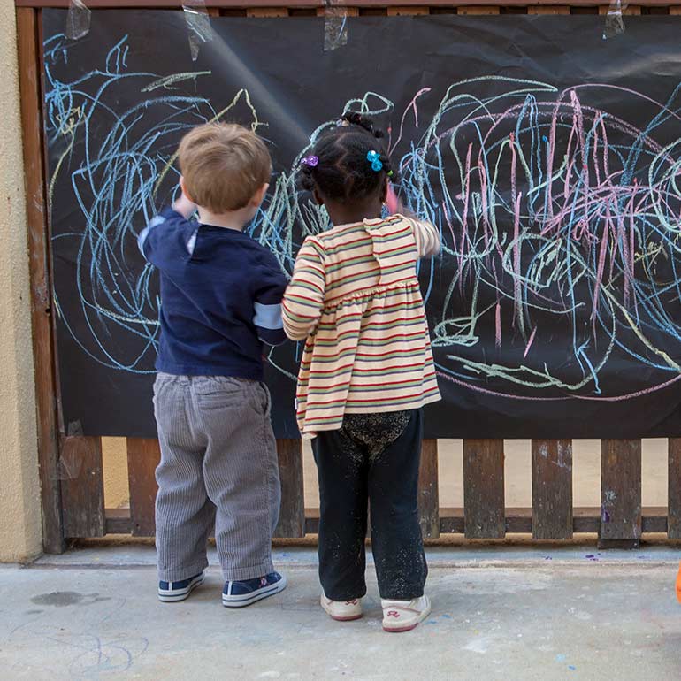 Bright Horizons Toddler Students drawing on the chalk board