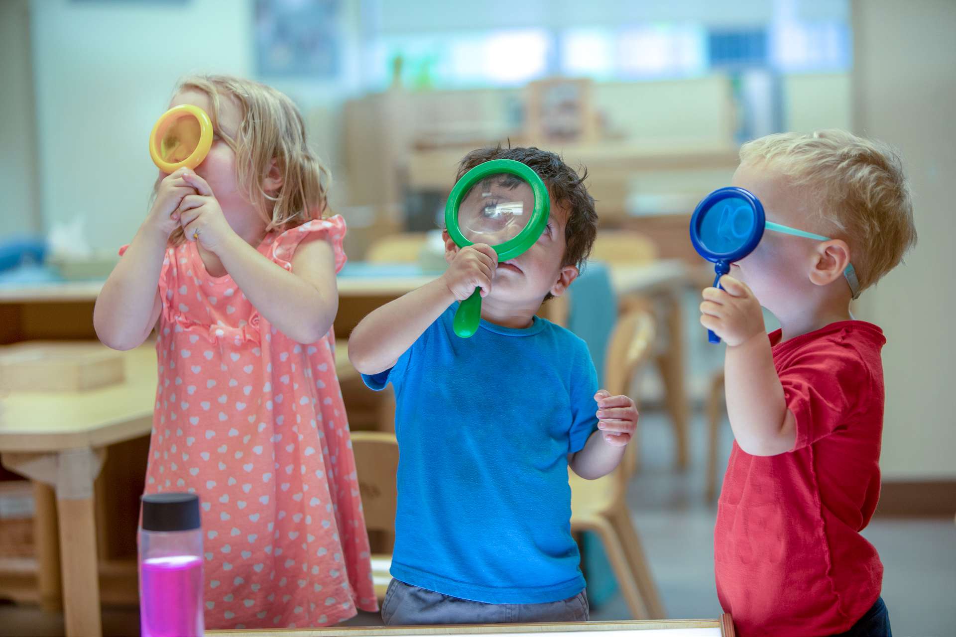 Young children explore their surroundings through magnifying glasses | Bright Horizon