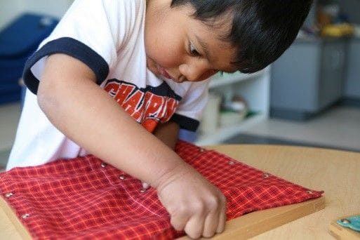 A young boy presses pins on fabric at daycare | Bright Horizons | Montessori