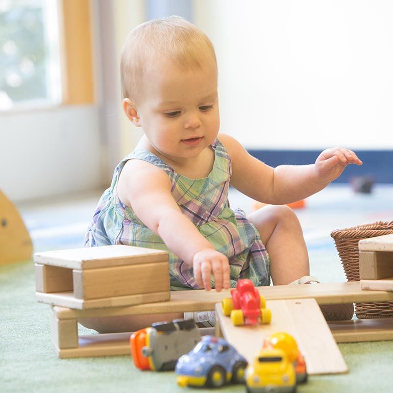 Bright Horizons infant playing with cars and ramps
