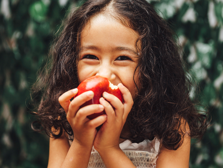 A young girl biting an apple with a big smile ?? 